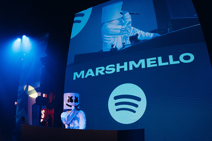 Marshmello is on stage at a DJ set wearing his signature mask